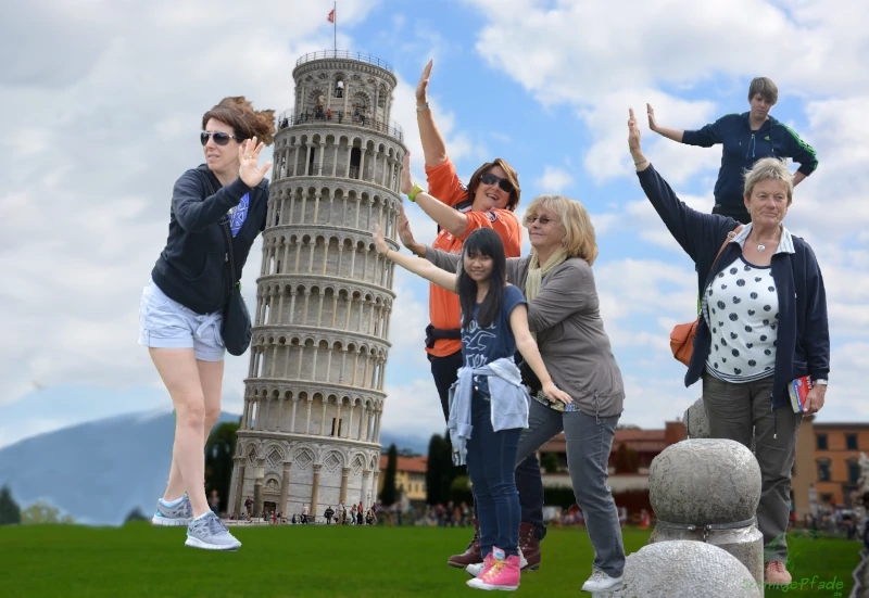 Tourists try to hold the leaning tower in Pisa, Italy