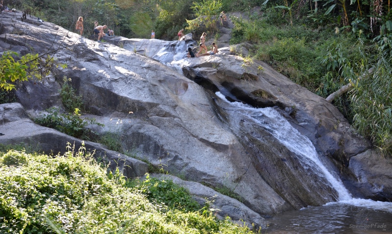 Backpackers sliding in the Mo Paeng waterfall in Northern Thailand